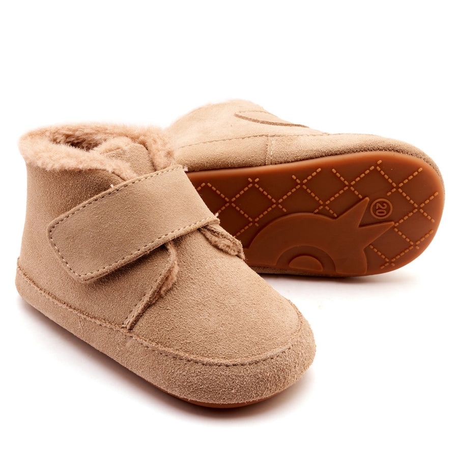 Pair of beige baby shoes with a strap on a white background