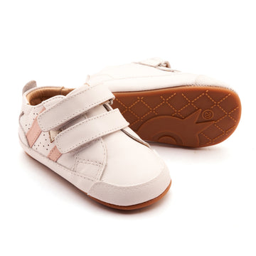 White children's shoes with brown soles on a white background