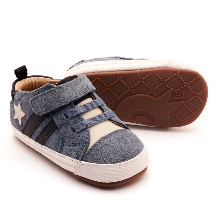 Pair of children's shoes with blue suede upper and white sole on a white background