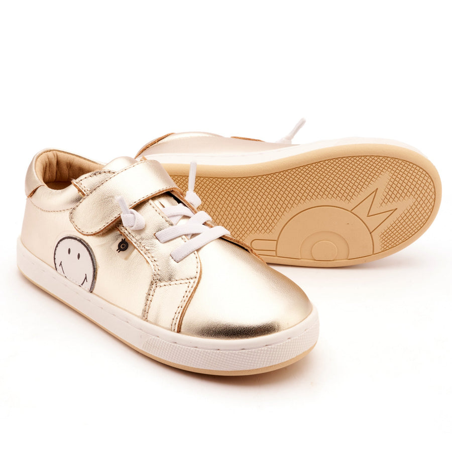 Gold children's sneakers with a smile face design on a white background