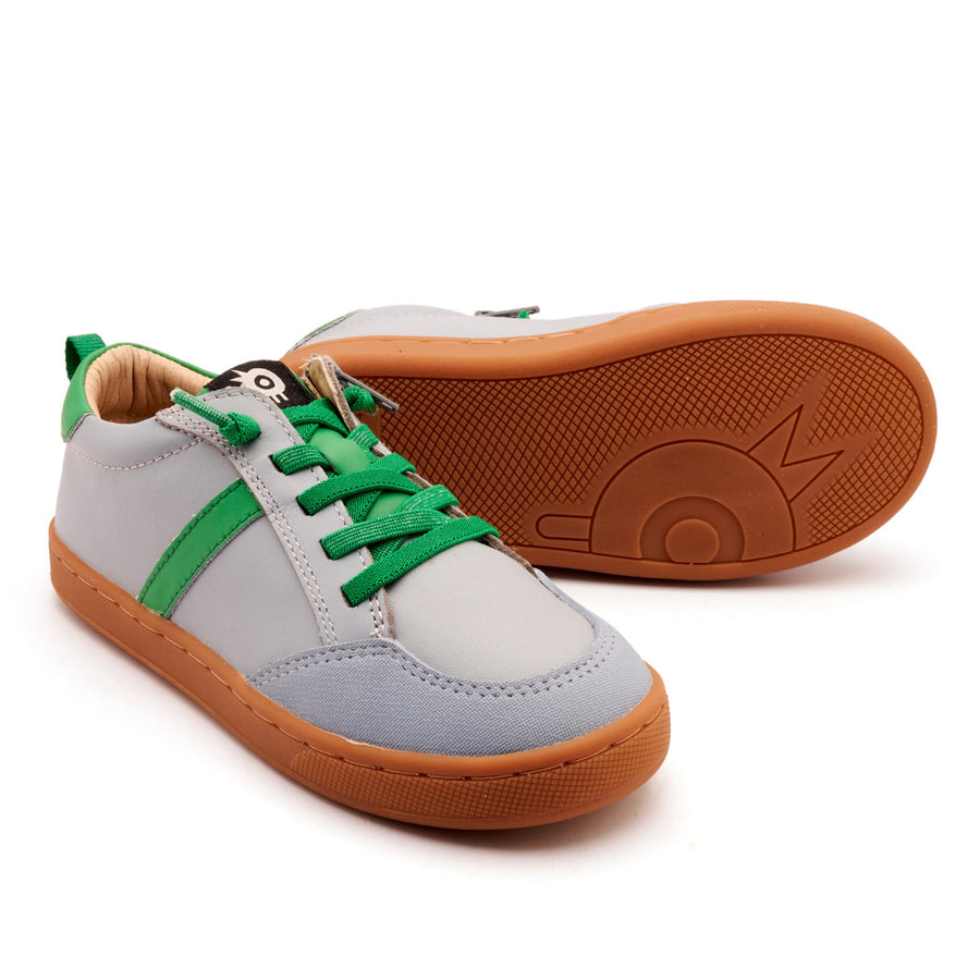 Pair of sneakers with green laces and brown soles on a white background