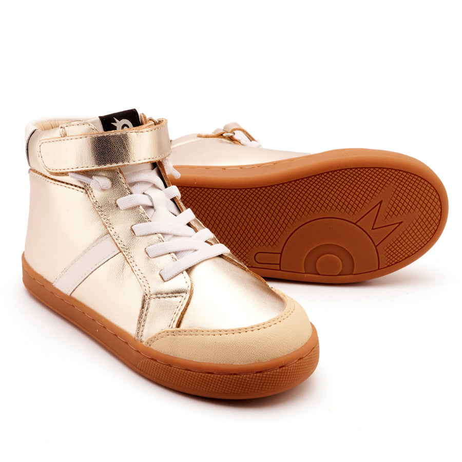 Pair of gold high-top sneakers with brown soles on a white background