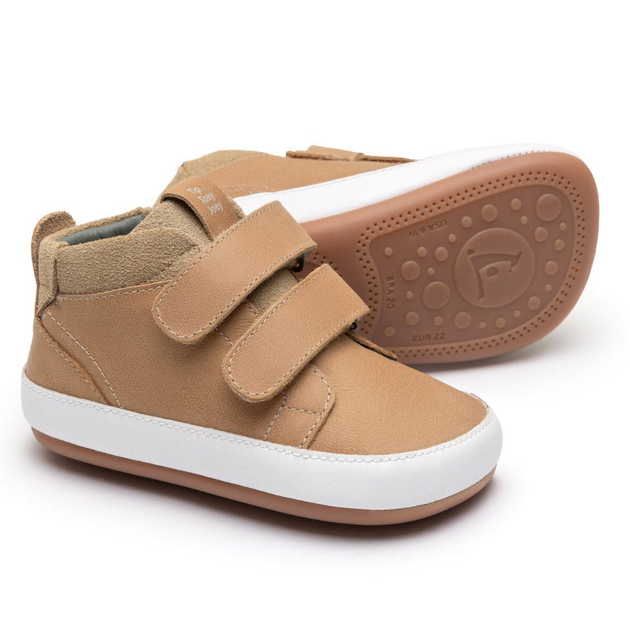 Tan children's shoe with a white sole on a white background